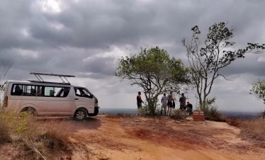Safari vehicle on a game drive through Shimba Hills National Reserve with elephants in the background