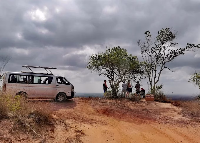 Safari vehicle on a game drive through Shimba Hills National Reserve with elephants in the background